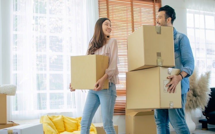 Smiling couple carrying moving boxes indoors in Capitola, CA