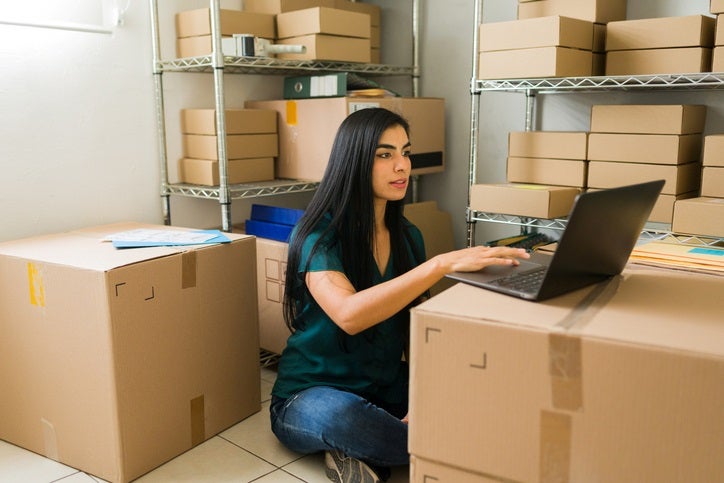 Woman using a laptop while organizing storage boxes in Capitola, CA